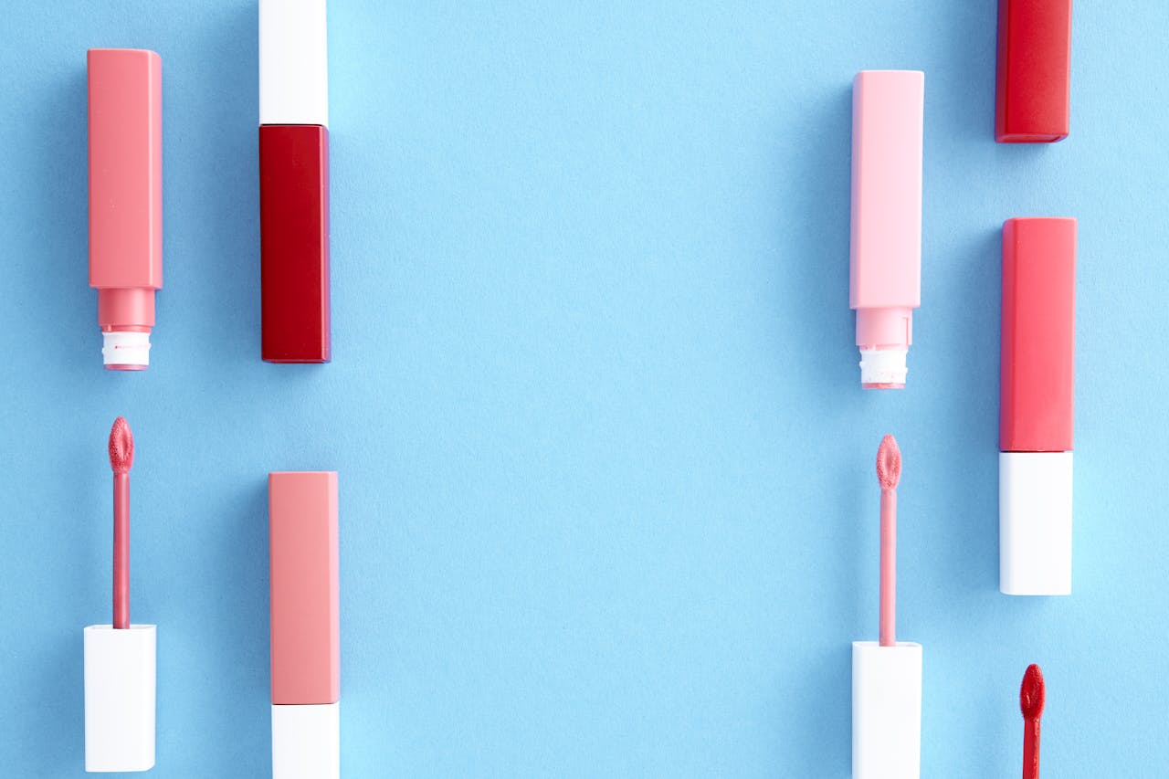Colorful lip gloss tubes laid out on a bright blue background, showcasing modern cosmetics.